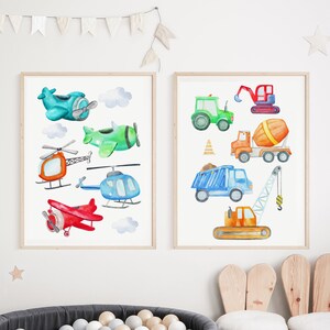 May include: Two framed watercolor prints featuring transportation vehicles. One print showcases airplanes and helicopters in various colors. The other print displays construction vehicles, including a tractor, dump truck, and crane.