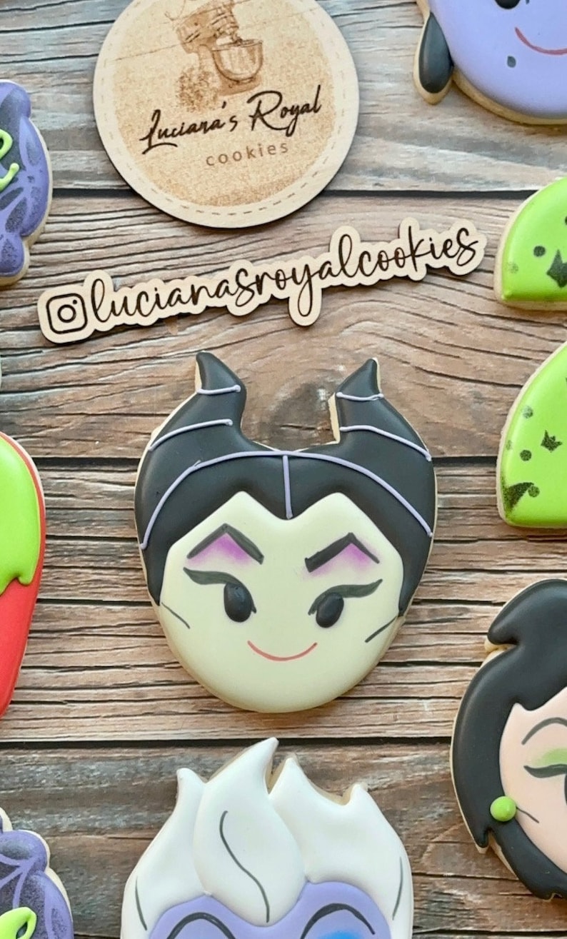 Peut inclure: Un ensemble de biscuits en sucre d&eacute;cor&eacute;s repr&eacute;sentant des personnages de films d'animation Disney. Les biscuits sont d&eacute;cor&eacute;s de gla&ccedil;age color&eacute; et de d&eacute;tails. Les biscuits sont dispos&eacute;s sur une surface en bois. Les biscuits sont &eacute;tiquet&eacute;s avec le texte "lucianaroyalcookies".
