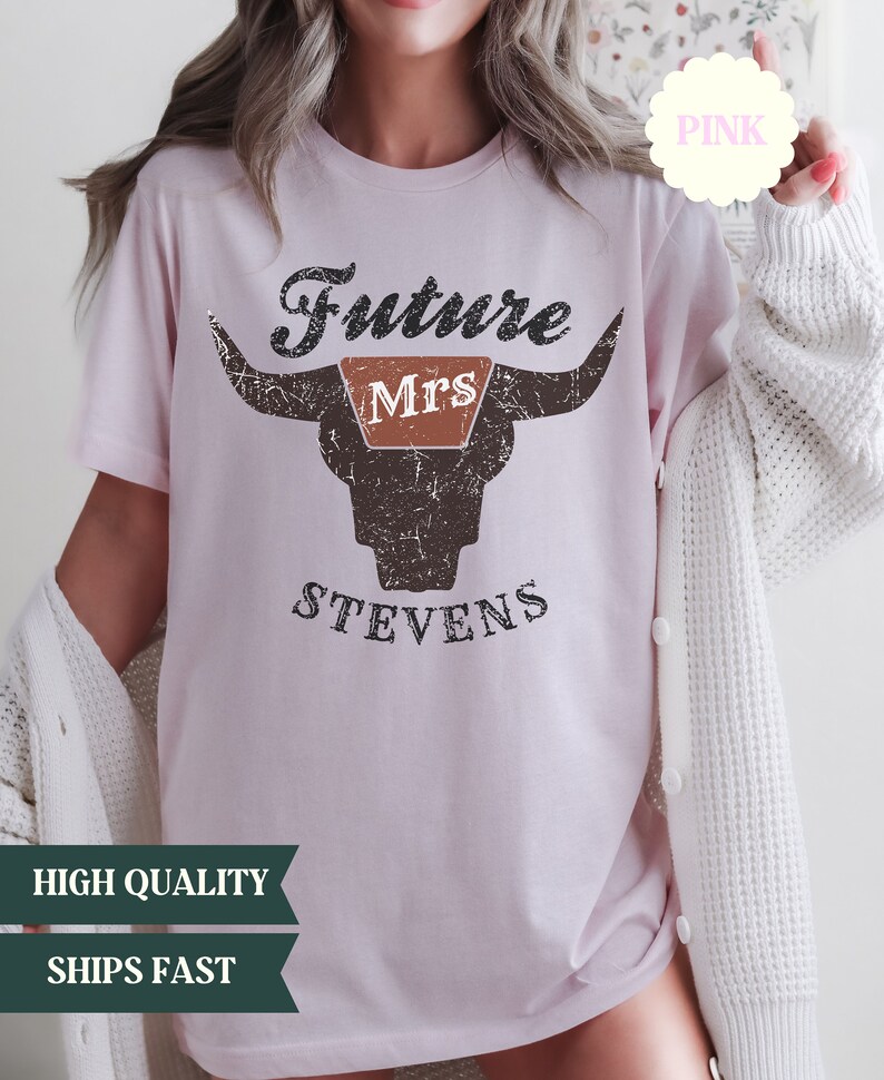 May include: Pink t-shirt with a distressed graphic of a bull's head with the text "Future Mrs. Stevens" on it.