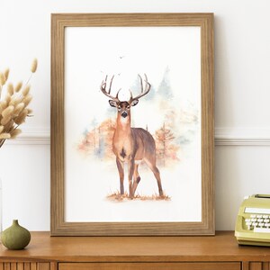 May include: A watercolor painting of a white-tailed deer standing in a forest. The deer is brown with a large rack of antlers. The background is a watercolor wash of brown, green, and blue.