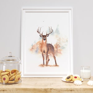 May include: A watercolor painting of a white-tailed deer standing in a forest. The deer is brown with a white underbelly and a large rack of antlers. The background is a soft watercolor wash of greens, browns, and blues.
