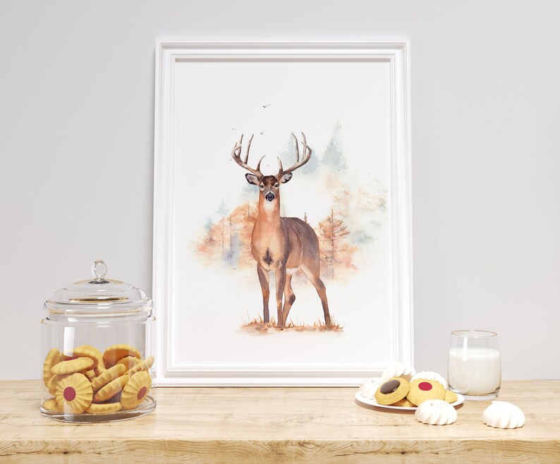 May include: A watercolor painting of a white-tailed deer standing in a forest. The deer is brown with a white underbelly and a large rack of antlers. The background is a soft watercolor wash of greens, browns, and blues.