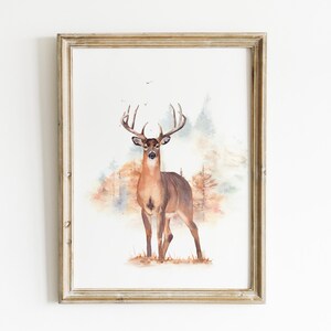 May include: Watercolor painting of a brown deer with large antlers standing in a forest setting. The background is a soft watercolor wash of blue, green, and brown.