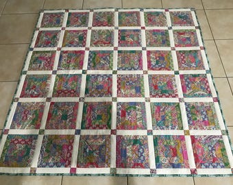 May include: A patchwork quilt with a white background and squares of various floral patterns in shades of pink, green, blue, and purple.