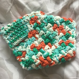 May include: Two crocheted dishcloths in a green, blue, white and orange colour pattern. The dishcloths are made with a textured stitch.