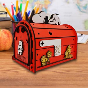 May include: A red wooden mailbox featuring Snoopy and Woodstock characters. The mailbox has a white sign that says "FOR YOU!" and a Snoopy figure on top. The mailbox has a plus sign and heart shapes.