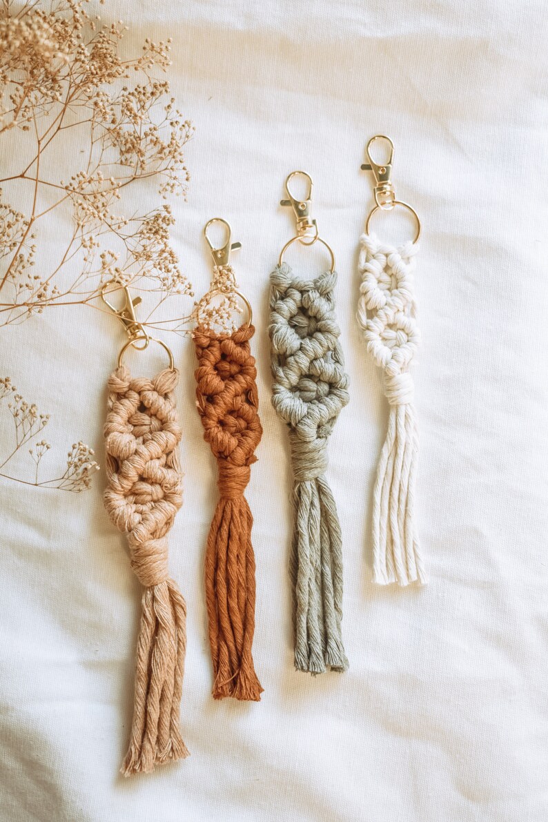 Pu&ograve; includere: Quattro portachiavi in macram&eacute; fatti a mano con nappe in beige, marrone, verde e bianco. I portachiavi sono attaccati a anelli portachiavi dorati.