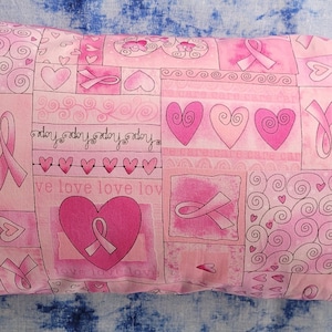 May include: Pink pillow with a patchwork design featuring hearts, swirls, and pink ribbons. The pillow has the text "hope hope hope hope" and "we love love lov" printed on it.