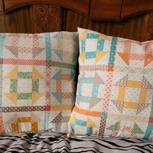 May include: Two decorative throw pillows with a patchwork design featuring a variety of colors and patterns, including blue, yellow, orange, green, and brown.