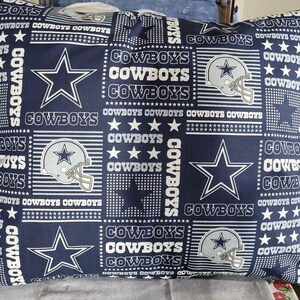 May include: A blue and white pillow with a repeating pattern of the Dallas Cowboys logo and the word "Cowboys".