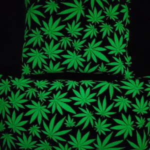 May include: Two black pillowcases with a green marijuana leaf pattern that glows in the dark.