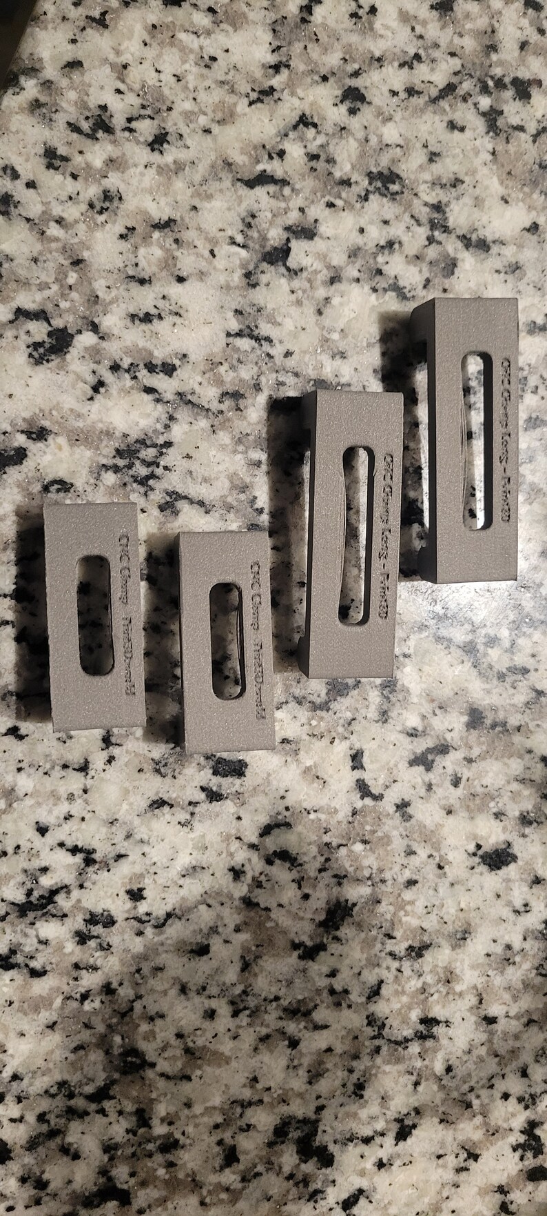Puede incluir: Cuatro bloques de metal gris con el texto "CNC Gear -  #120141" impreso en cada bloque.