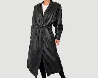 May include: A long black leather coat with a belt and button closure. The coat has a collar and long sleeves.