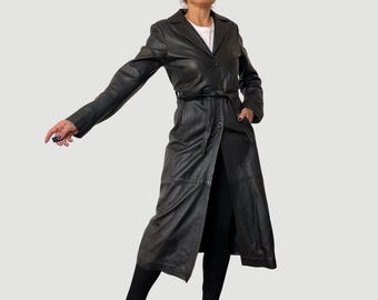 May include: A long black leather trench coat with a belt and a single button closure.