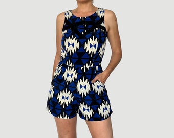 Op de afbeelding: Een mouwloze jumpsuit met een geometrische print in blauw en wit en een zwarte afwerking rond de halslijn.