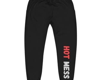 May include: Black sweatpants with a drawstring waist and pockets. The words "HOT MESS" are printed vertically in red and white on the left leg. The text has a distressed, vintage look.