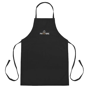 May include: Black apron with a large pocket and adjustable straps. The apron has a white embroidered logo that says "PAW-DRE" with a paw print above the word "DRE".