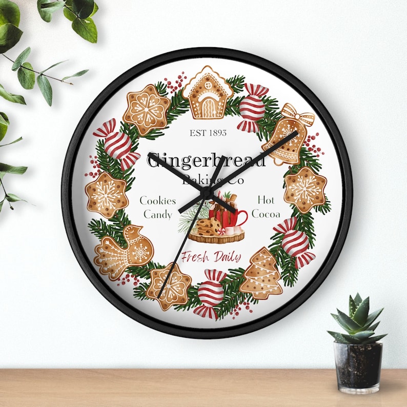 Gingerbread baking co wreath, with cookies, candy and hot cocoa text in green font.  Fresh Daily in red font. Available in black, white and wood surround.  A choice of black or white clock hands.