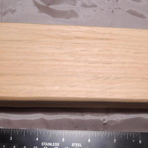 May include: A light brown wooden oval-shaped box with a smooth surface.