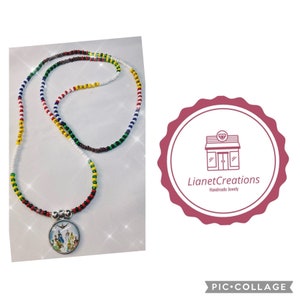 May include: A multi-colored beaded necklace with a round pendant featuring a colorful image of people. The necklace is made of white, red, green, yellow, and brown beads. The pendant is silver with a clear glass cover. The necklace is displayed on a white background with a pink and white logo that says "LianetCreations Handmade Jewelry".