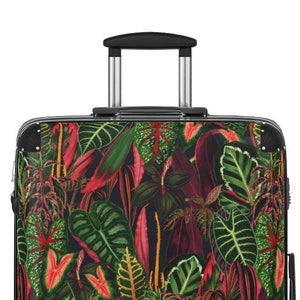 Two tropical-themed suitcases with a vibrant jungle-inspired design featuring green leaves, pink flowers, and colorful birds on a white background.