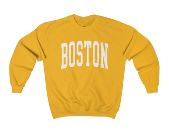 Op de afbeelding: Een geel sweatshirt met het woord "BOSTON" in wit op de voorkant.