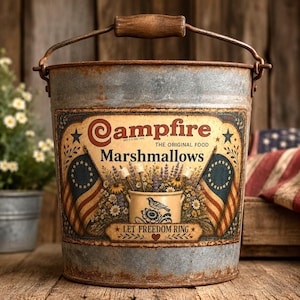 May include: A galvanized metal bucket with a rusted finish and a wooden handle. The front features a label for Campfire Marshmallows with American flags, floral illustrations, a bird, and the text Let Freedom Ring in a decorative frame.