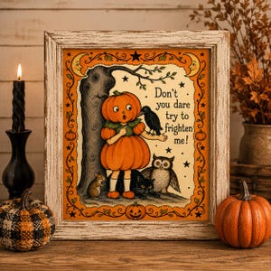 May include: A framed print featuring a vintage-style illustration of a child in a pumpkin costume standing by a tree with a crow, an owl, a mouse, and a black cat. The text reads, Don't you dare try to frighten me! The border is orange with stars.