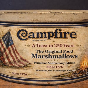 May include: Vintage Campfire Marshmallows tin with an American flag illustration. The tin reads "A Toast to 250 Years" and "Since 1776." The design includes a campfire and text that says "The Original Food Marshmallows."
