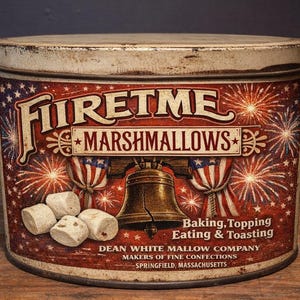 Könnte beinhalten: Vintage Metallbehälter mit "Firetme Marshmallows" und patriotischem Design. Das rot-weiß-blaue Etikett zeigt Feuerwerk, die Freiheitsglocke und Text, der darauf hinweist, dass das Produkt zum Backen, Belegen, Essen und Toasten geeignet ist.