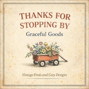 May include: A square sign with a beige, textured background featuring the text THANKS FOR STOPPING BY, Graceful Goods, and Vintage Finds and Cozy Designs. A red wagon filled with colorful flowers is centered between the lines of text.