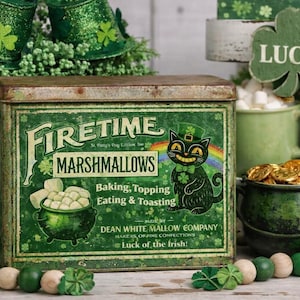 Könnte beinhalten: Eine grüne Vintage-Dose mit "Firetime Marshmallows" mit einer Cartoon-Katze mit einem Koboldhut, einem Regenbogen und einem Topf mit Marshmallows. Weitere Dekorationen zum St. Patrick's Day sind ein Goldtopf, Kleeblätter und grüne Tassen.