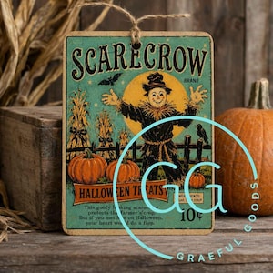 May include: A rectangular hanging sign with a vintage-style illustration of a scarecrow in a field with pumpkins. The text reads SCARECROW BRAND, HALLOWEEN TREATS, and includes a short poem. The sign features a weathered teal background and a jute string.