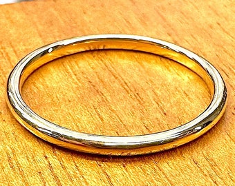 May include: A simple gold band ring, a classic wedding band style.