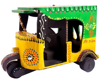 May include: A handcrafted wooden auto-rickshaw painted in bright yellow and green. The vehicle features decorative floral patterns, a beaded trim, and the text "गीत 30 km." on the side. The wheels and interior are black.