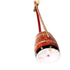 May include: A red and gold stringed instrument with floral patterns. The instrument has a cylindrical body and a long neck. The body is decorated with red and gold floral designs, and the neck is a light brown colour.
