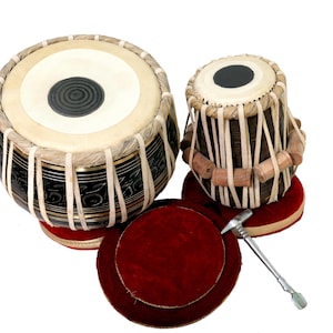 May include: A pair of brown and black tabla drums with red cushions and a metal stick. The drums are made of wood and have a traditional Indian design.