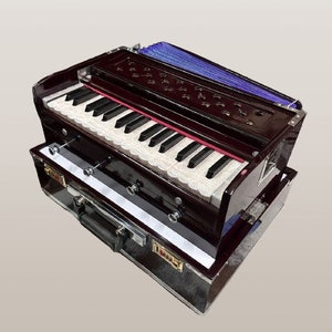 May include: A dark brown harmonium with a blue bellows and a white keyboard. The harmonium is in a black carrying case.