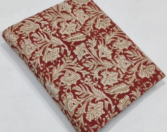 May include: Folded fabric with a repeating floral and bird pattern in cream and red. The fabric appears to be cotton or a similar material, suitable for quilting, sewing, or crafting projects. The design features stylized flowers and birds.