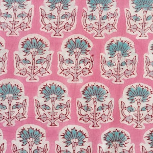 May include: Close-up of a pink fabric with a repeating floral pattern. The design features stylized flowers in teal and white, outlined with maroon details. The flowers are set against a solid pink background, creating a vibrant and eye-catching textile.