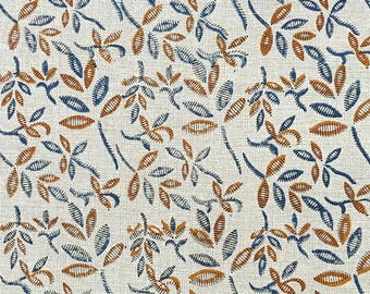 Könnte beinhalten: Nahaufnahme eines cremefarbenen Stoffes mit einem sich wiederholenden Muster aus stilisierten Blättern und floralen Elementen. Die Blätter sind in Blau- und Brauntönen gehalten und erzeugen ein strukturiertes, organisches Design. Der Stoff hat ein gewebtes Aussehen.