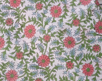 May include: White fabric with a repeating floral pattern. The design features pink flowers with green centers, green vines, and blue leaves. The fabric is likely cotton or a similar material, suitable for various craft projects.