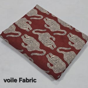 May include: Voile fabric with a repeating pattern of stylized tigers in cream against a deep red background. The fabric is folded, showing the pattern's layout. The text "voile Fabric" is printed at the bottom of the image.