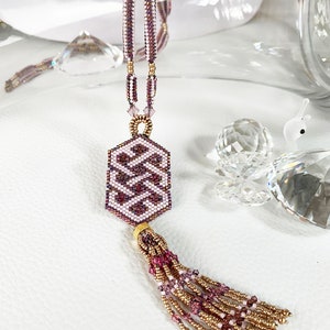 May include: A pink and gold beaded necklace with a geometric pendant and a tassel. The pendant is a hexagon shape with a repeating pattern of pink and white beads. The tassel is made of pink and gold beads.