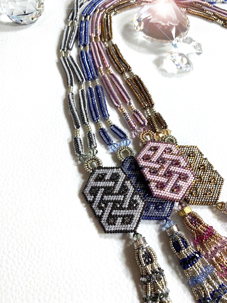 May include: A multi-strand beaded necklace with a geometric pattern and tassels. The necklace is made of silver, blue, purple, and gold beads. The tassels are made of silver, blue, and purple beads.