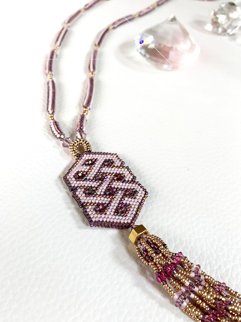 May include: A pink and gold beaded necklace with a geometric pendant and a tassel. The pendant is a hexagonal shape with a pink and gold pattern. The tassel is made of pink and gold beads.