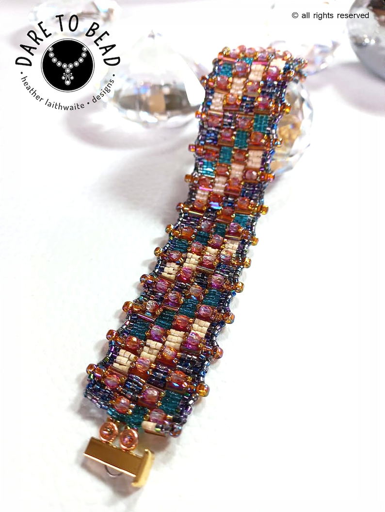 May include: A beaded bracelet with a geometric pattern in shades of teal, purple, pink, and cream. The bracelet has a gold clasp.