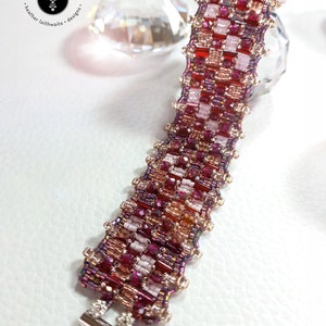 May include: A beaded bracelet with a silver clasp. The bracelet is made with red, pink, and gold beads in a geometric pattern.