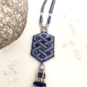 May include: A blue and silver beaded necklace with a geometric pendant and a tassel. The pendant is a hexagon shape with a silver bead in the center. The tassel is made of blue and silver beads.