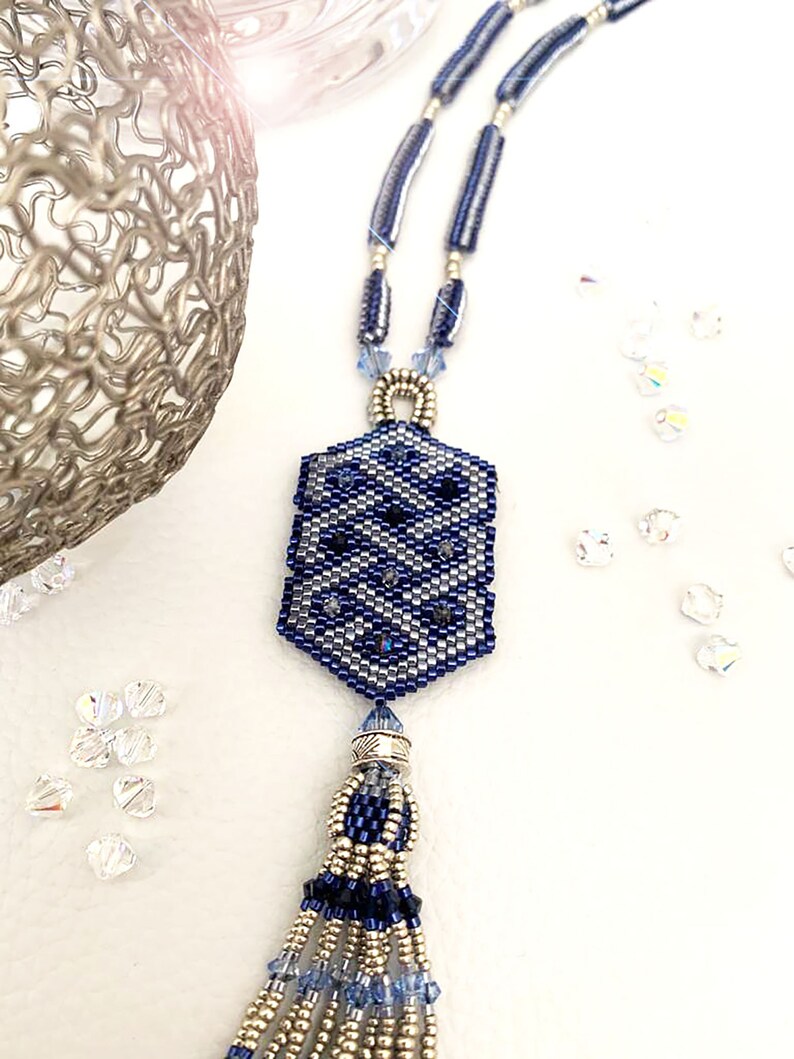 May include: A blue and silver beaded necklace with a geometric pendant and a tassel. The pendant is a hexagon shape with a silver bead in the center. The tassel is made of blue and silver beads.
